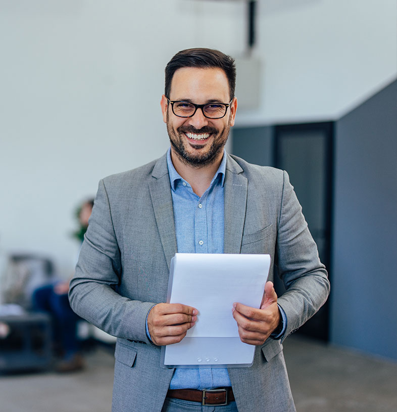 A man smiling in a suit holding a tablet. - Vision Law®