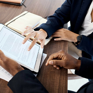 Close-up of two people's hands reviewing a legal document on a tablet during a business meeting.